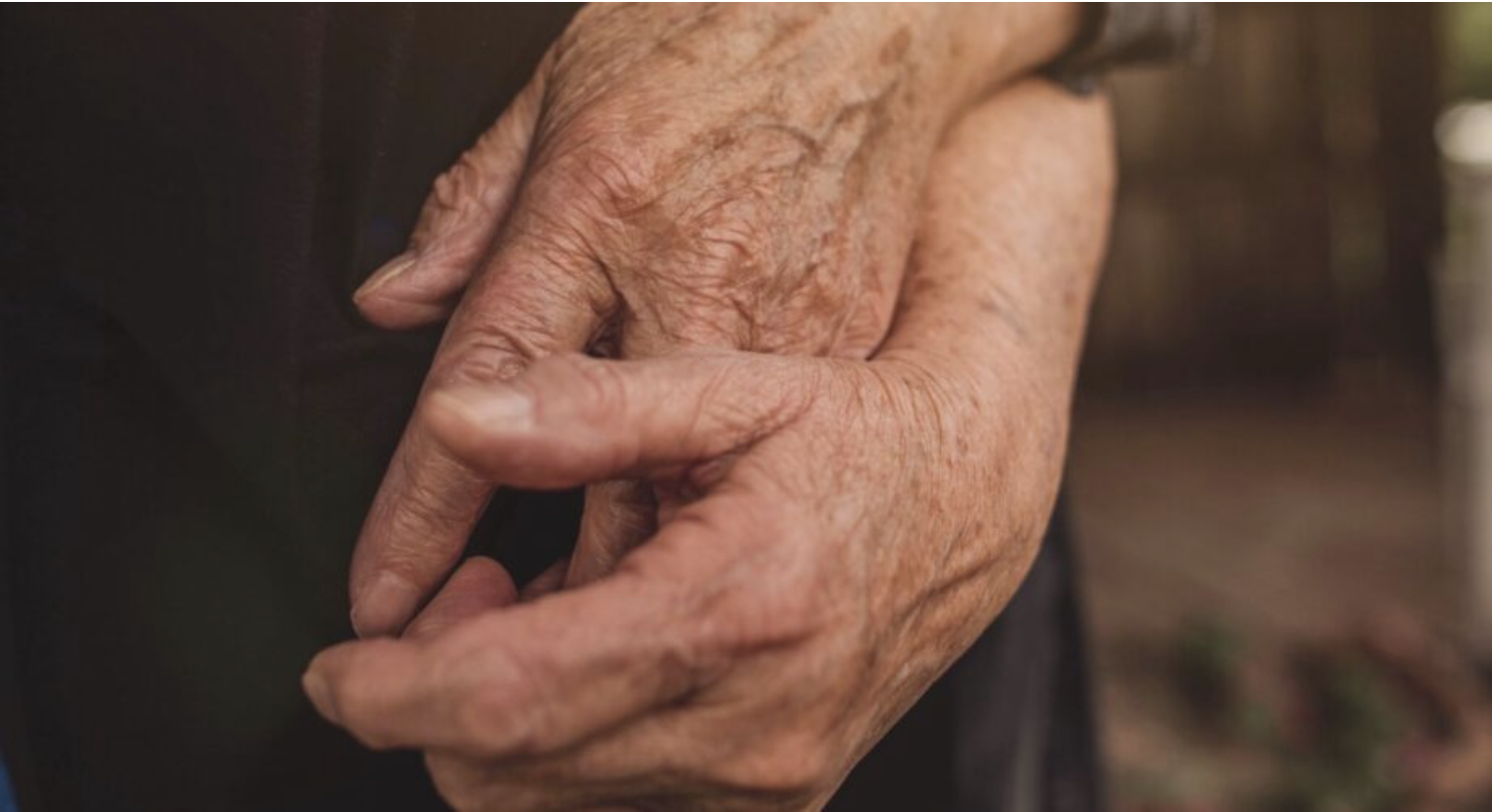 Wrinkly hands held together, likely a couple.